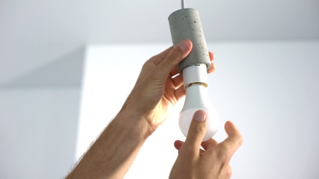 Male hands twisting electrical saving lightbulb, energy efficiency, closeup