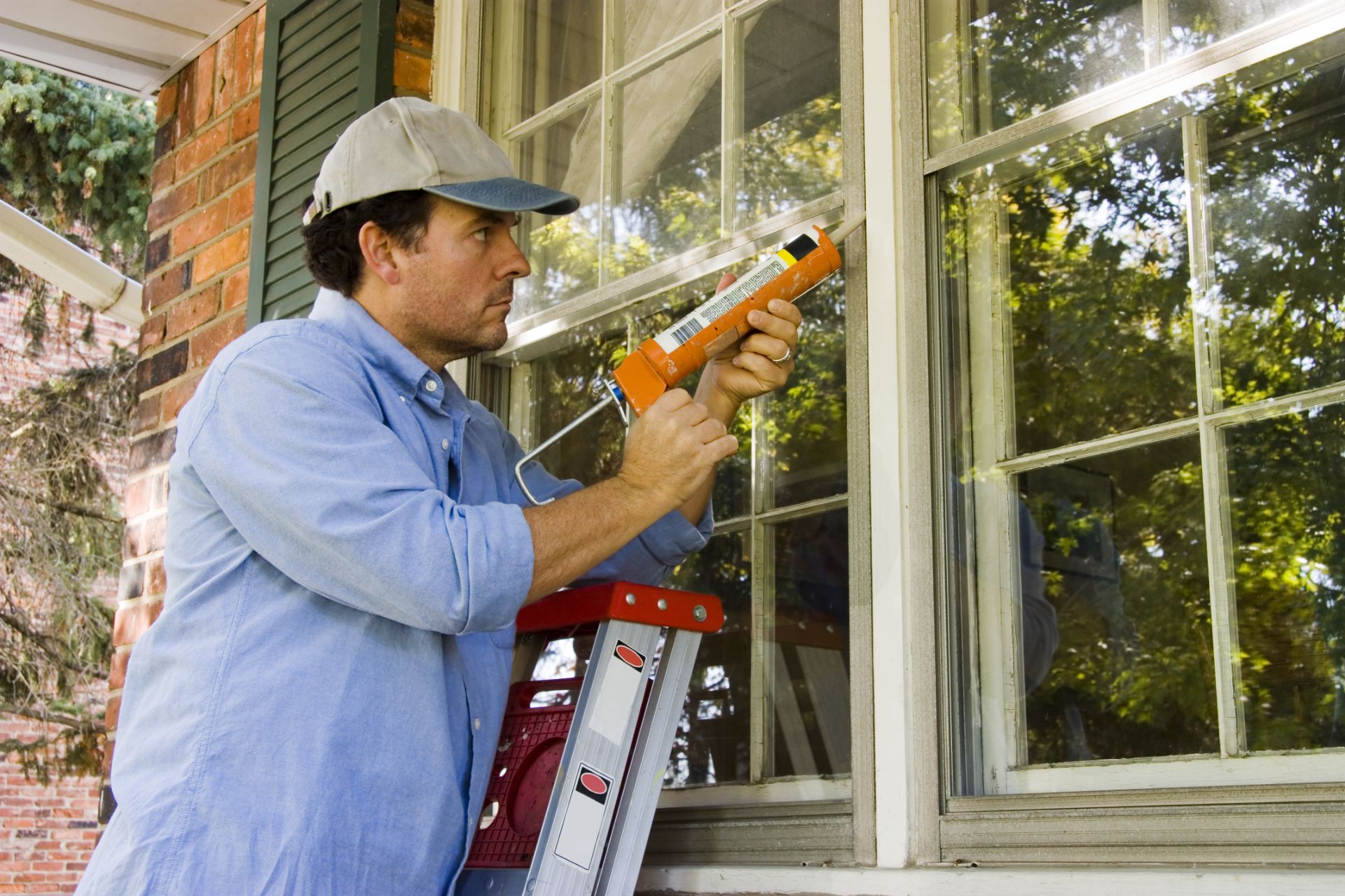 Man caulks his windows to air seal and insulate his home