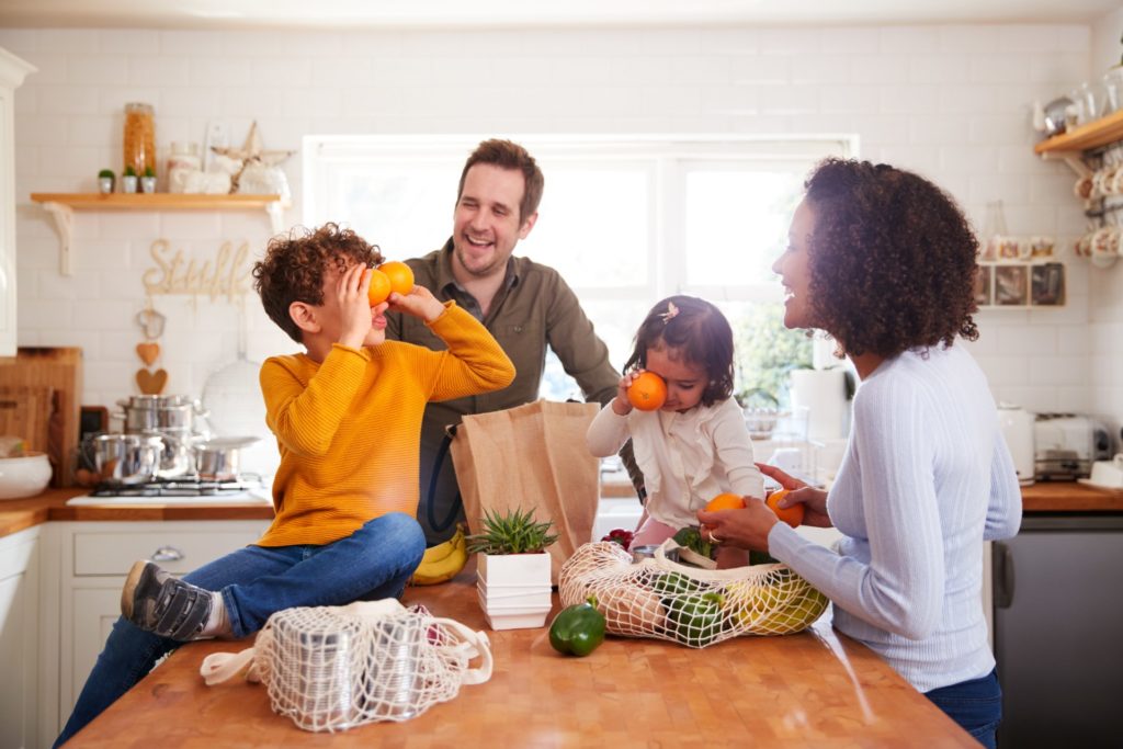 A family unpacking fruits and vegetables from reusable grocery bags