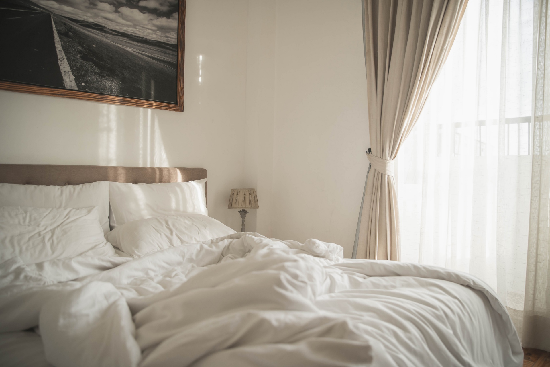White interior of cozy bedroom with morning light. Cozy bedroom beside window and sunlight in the morning horizontal background.
