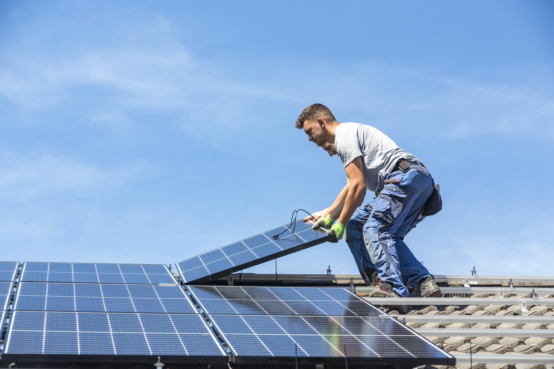 A man installing solar panels on a terracotta roof